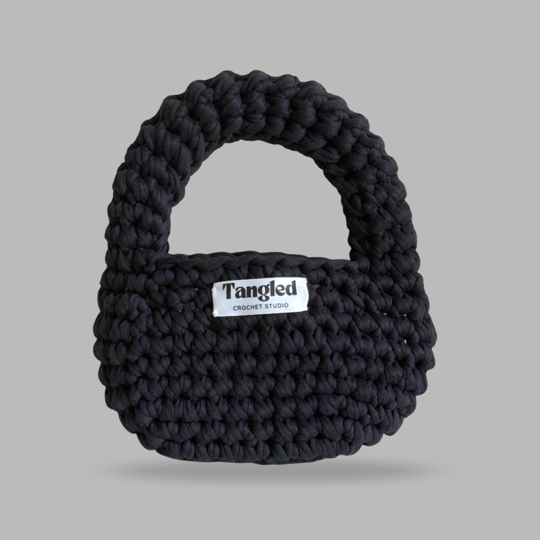 Trendy round crochet handbag, made from 100% recycled cotton, adding a unique touch to any outfit.