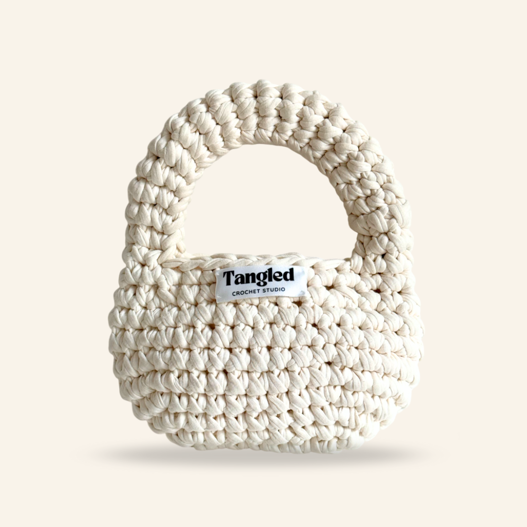 Trendy round crochet handbag, made from 100% recycled cotton, adding a unique touch to any outfit.