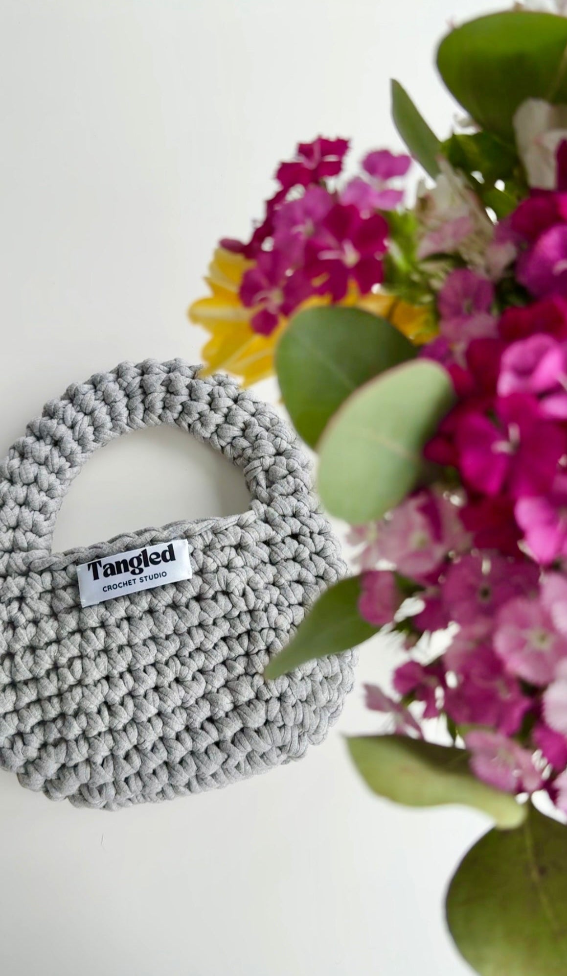 Trendy round crochet handbag, made from 100% recycled cotton, adding a unique touch to any outfit.